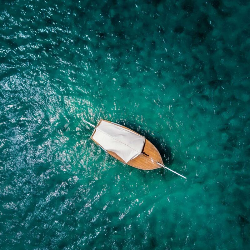 A bird's eye view of a wooden boat drifting in the ocean.