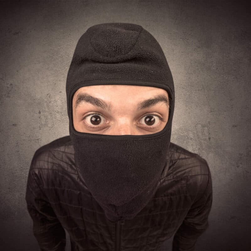A thief wearing a balaclava staring at the camera rather bewildered.